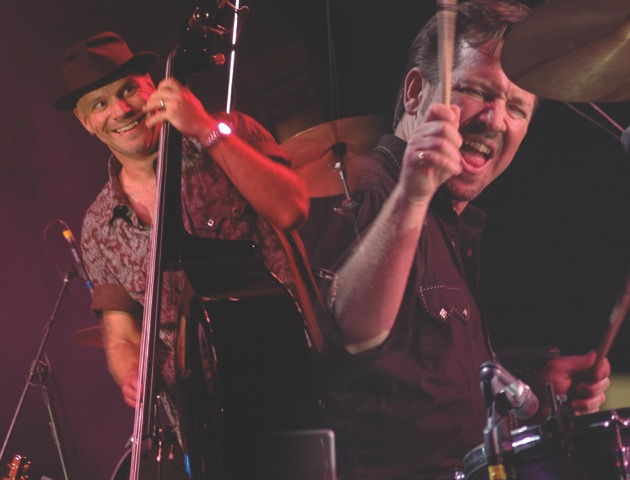 Two musicians performing under red stage lighting