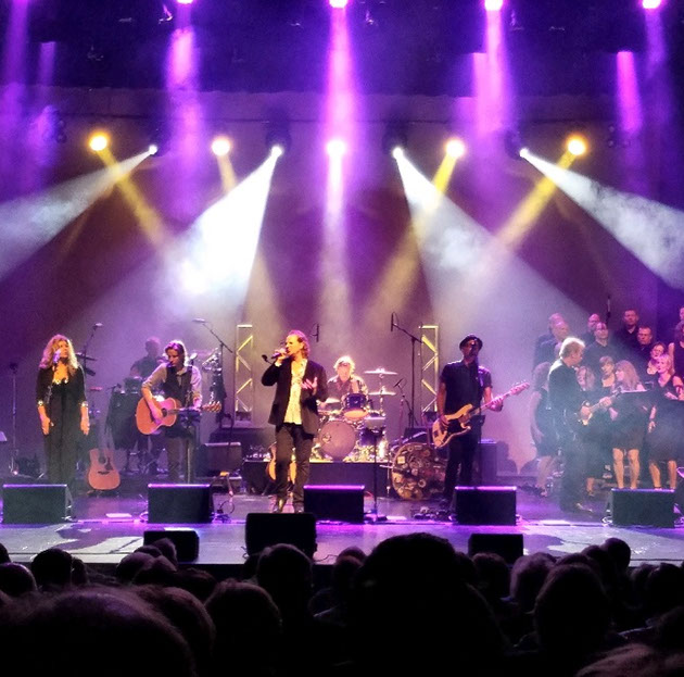 Full band on stage with purple and white lighting